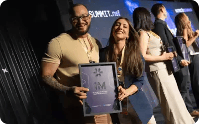 Imagem-Casal de alunos com placa de faturamento 1M
